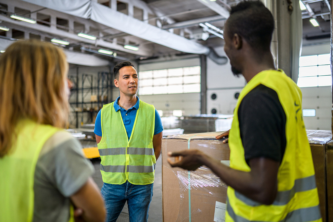 Diverse warehouse workers standing in the middle of the warehouse having an informal meeting