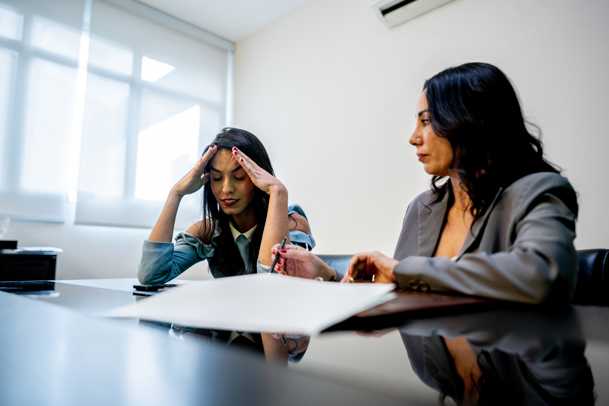 Worried young woman talking to coworker at office