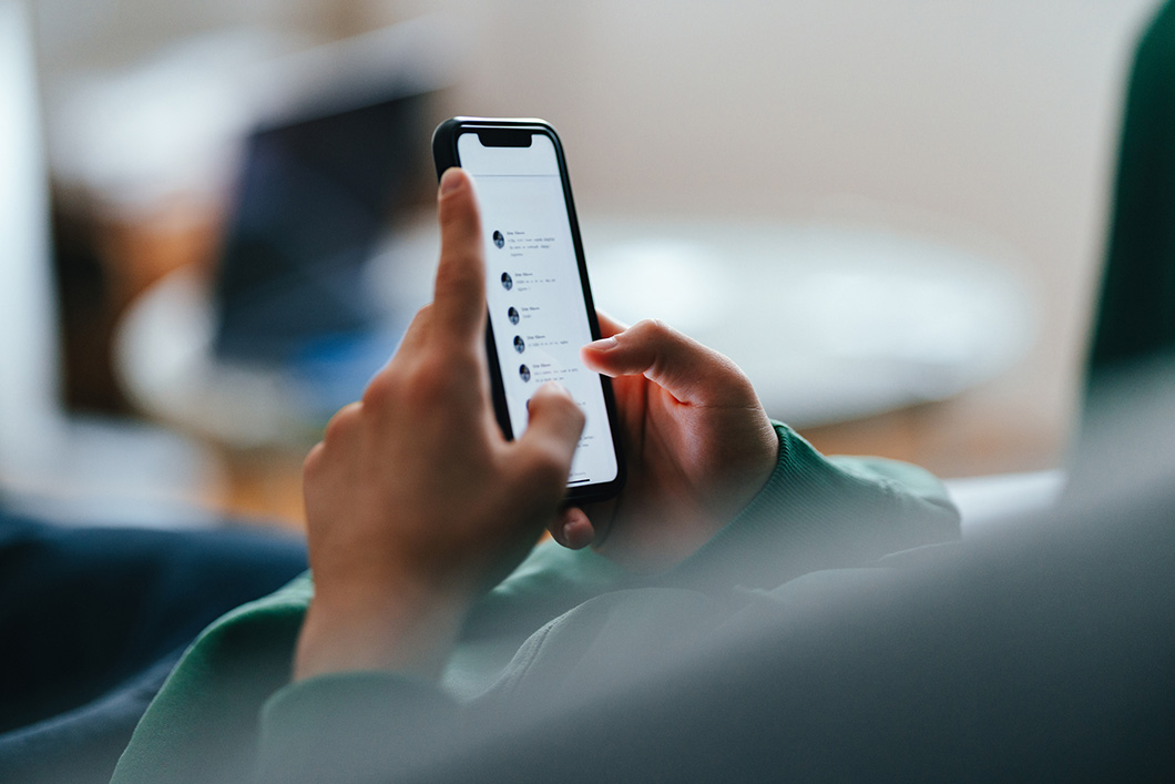 Close up or a persons hands on a mobile phone scrolling through social media