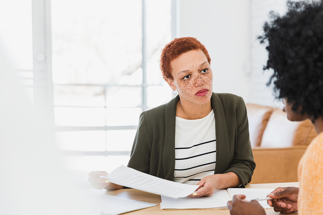 The mid adult female advisor or lawyer listens with a very serious look on her face to the unrecognizable female client.