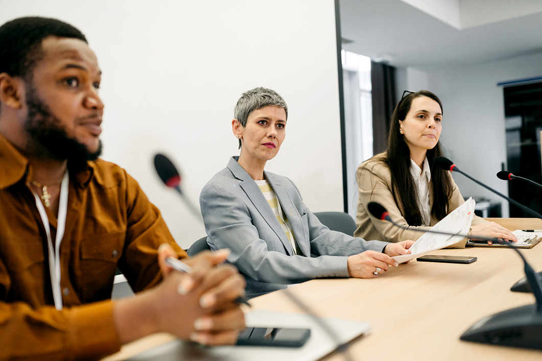 A panel of people with microphones listening during a hearing.