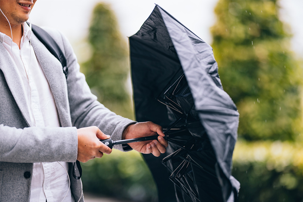 Close up photo of man hands opening black umbrella at the city street.
