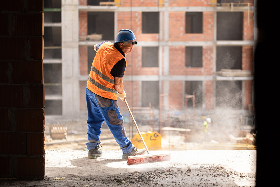 Construction worker using broom to clean the dust on construction site