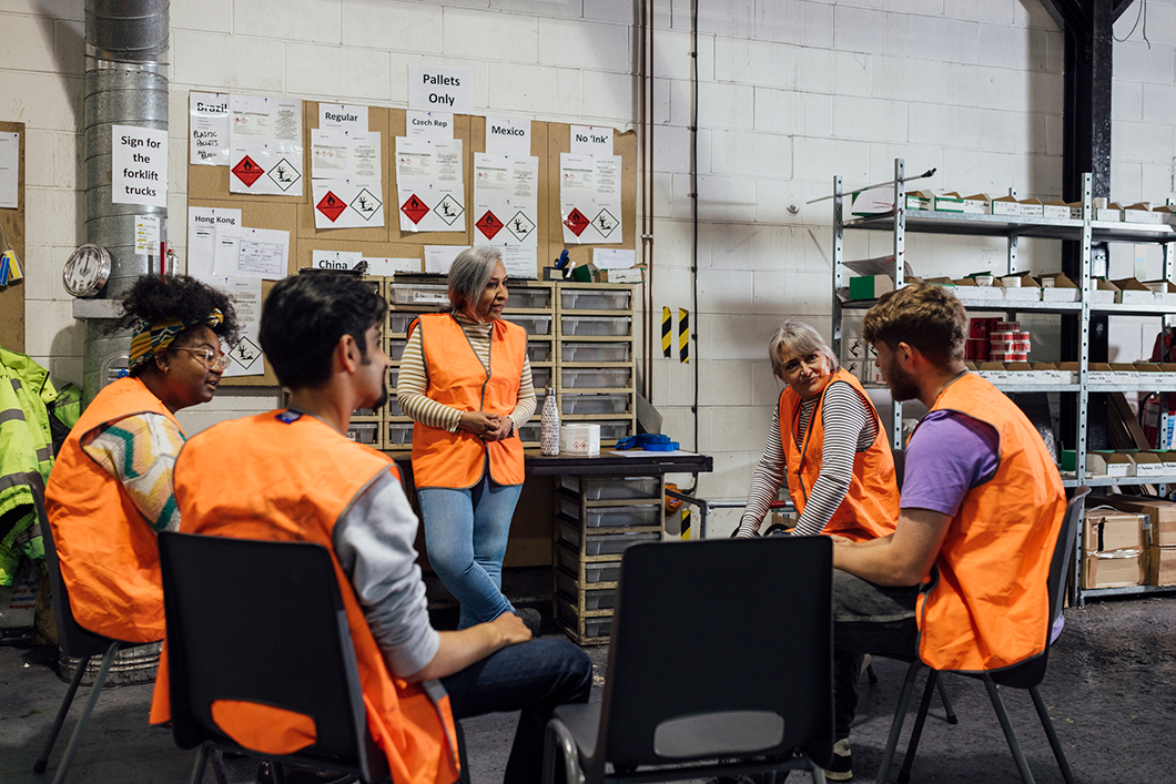 Group of factory workers gathered around in a meeting