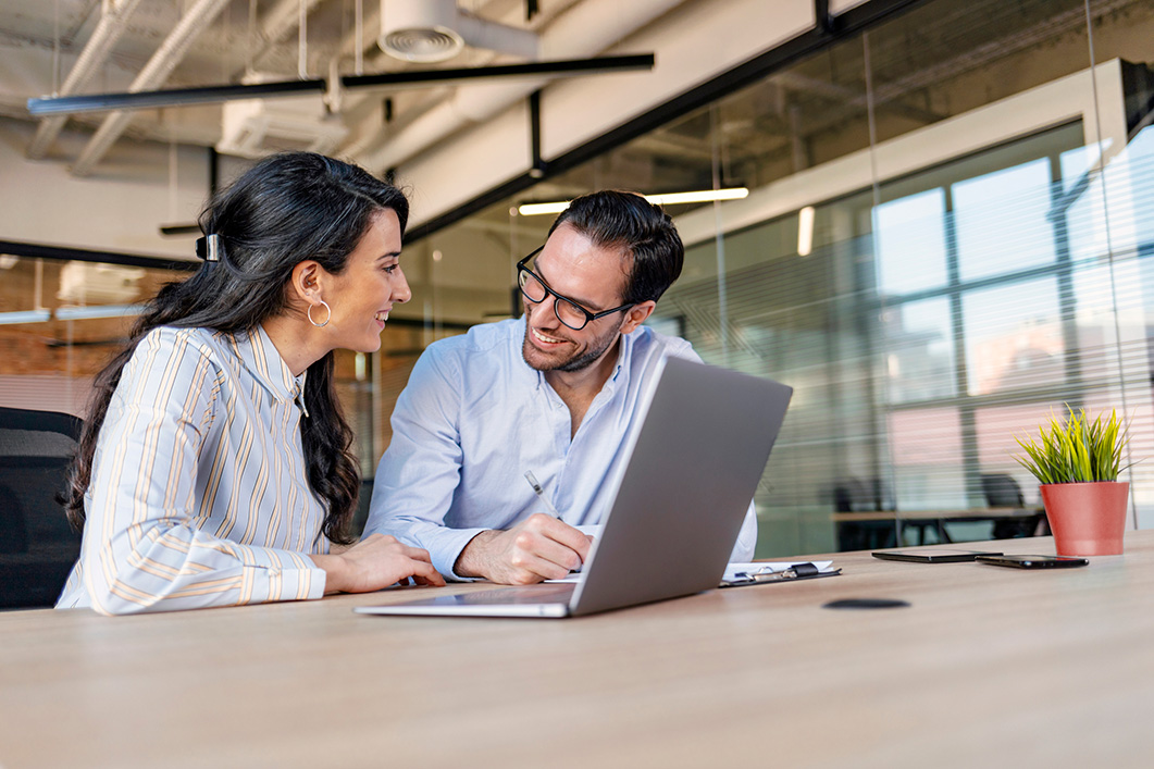 Business colleagues sat smiling warmly at each other in an office environment