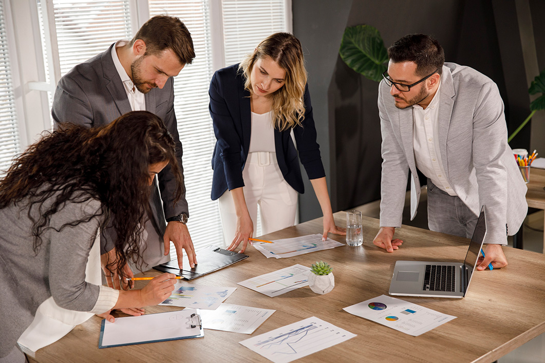 A group of colleagues look over paperwork on a table.