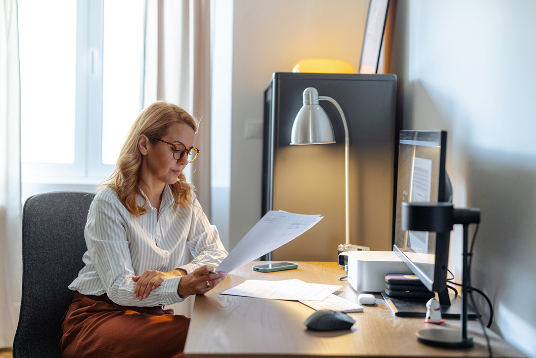 A woman sits at a desk looking at papers.