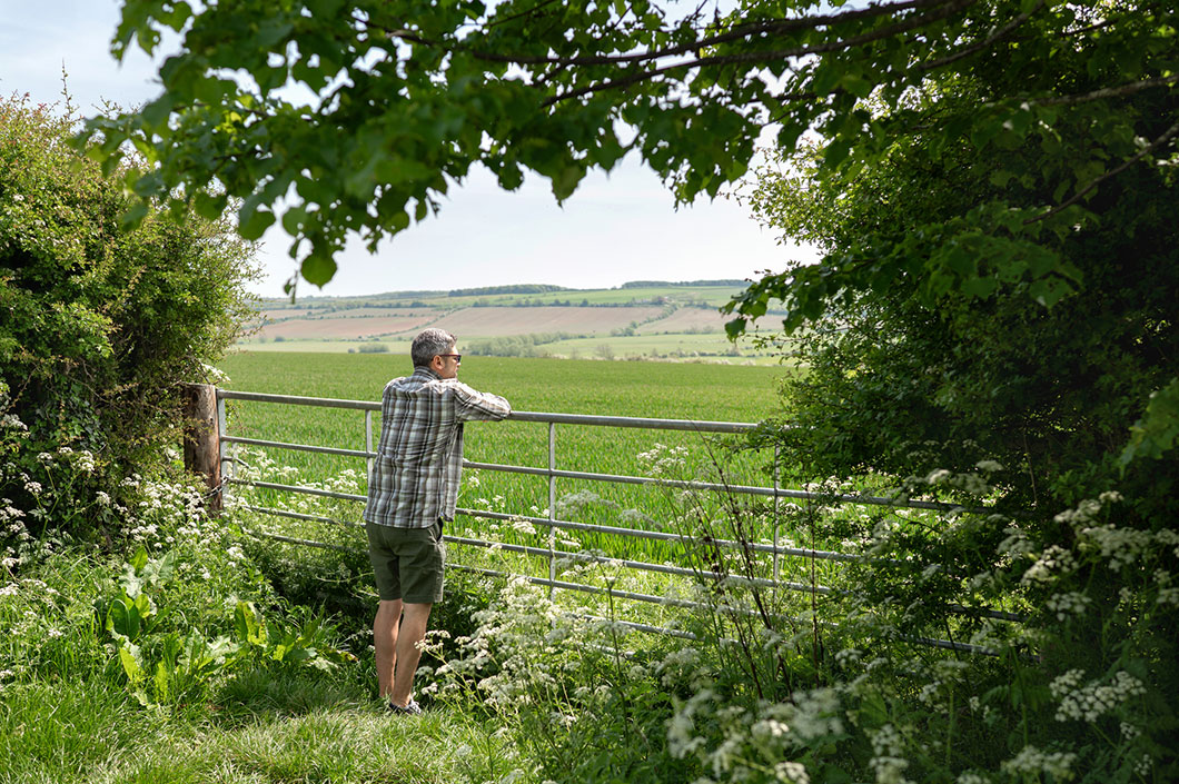 A person stands at the edge of a field.