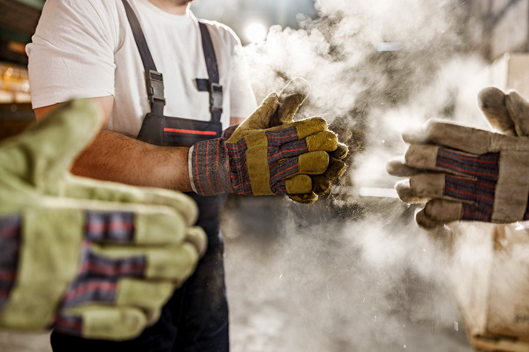 Workers wear gloves and there is a lot of dust around.